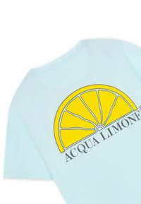 Ljusblå t-shirt i bomull med en stor grafisk bild av en gul citronskiva och texten "ACQUA LIMONI" nedanför i svart. Korta ärmar och rundad halsringning.