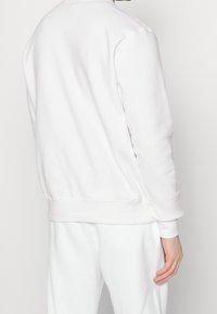 Sudadera blanca, mezcla de algodón, corte clásico de cuello redondo, mangas largas, puños y dobladillo acanalados, textura suave, diseño minimalista, parte trasera sin adornos.