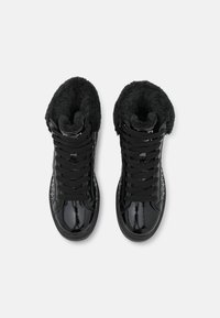 Černé vysoké tenisky vyrobené z lesklé lakované kůže, s měkkým černým kožíškem uvnitř, texturovanými panely a plochými černými tkaničkami.