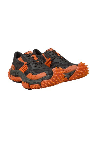 Schwarz-orange Sneaker mit strukturierten, stacheligen Sohlen und Mesh-Details, entworfen für hohe Traktion und markanten Stil.