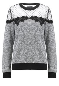 Grijze trui met een zwarte kanten overlay en doorschijnende mesh met stippen op de schouders. Geribbelde boorden en zoom in zwart.