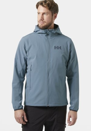 Mann trägt hellblaue Kapuzenjacke mit Frontreißverschluss und mit Reißverschluss versehene Seitentaschen, blickt nach links vor einfarbigem Hintergrund.