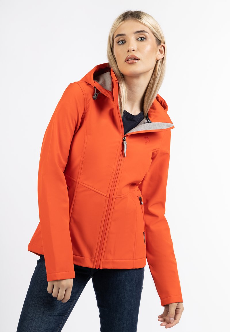 Giacca softshell arancione con cappuccio, dotata di chiusura con zip, fodera grigia a contrasto e cuciture strutturate. Indossata con jeans scuri.
