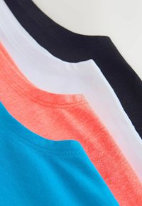 Pile de t-shirts pliés avec des encolures noires, blanches, corail et bleues vue en gros plan.