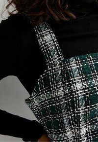 Abito a quadri verdi e neri in tessuto intrecciato testurizzato, con scollatura quadrata e spalline spesse.