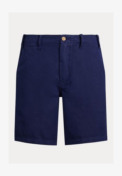 Βαμβακερά σορτς σε ναυτικό μπλε με μπροστινό κλείσιμο με κουμπί, θηλιές για ζώνη και λεία υφή. Ευθεία γραμμή μέχρι το γόνατο με ελάχιστες λεπτομέρειες.