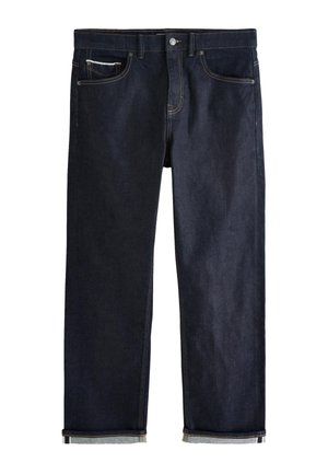 Temno modre kavbojke iz jeansa z klasičnim ravnim krojem, ki imajo pet žepov, zapenjanje na gumbe in zavihane robove, ki razkrivajo svetlo modro podlogo.