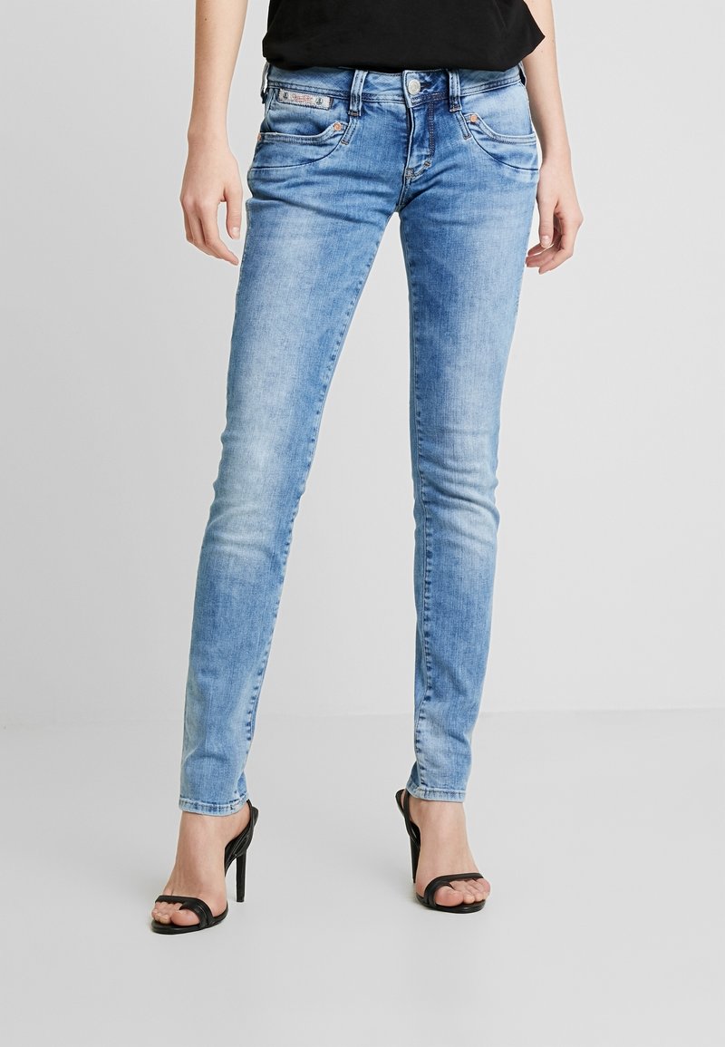 Blekta blå skinny jeans med normal hög midja, femfickorsdesign och sömnadsdetaljer på bakfickorna. Gummilogoapplikation på midjebandet.