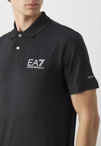 Schwarzes Polohemd aus leichtem Stoff mit Kragen, Knopfdetails und dem EA7 Emporio Armani Logo auf der Brust und dem Ärmel.