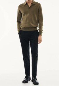 Olive green knit polo shirt with a collar, paired with slim-fit black trousers and black lace-up shoes. Smooth texture, minimal design.
