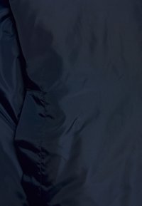 Mörk marinblått tyg med synliga sömmar och subtila veck, som visar en jämn, något glansig yta.