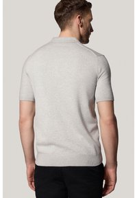 Dzianinowa koszulka polo z krótkim rękawem w jasnoszarym kolorze, z prążkowanym kołnierzykiem i mankietami, o dopasowanym kroju. Gładka faktura i klasyczna sylwetka.