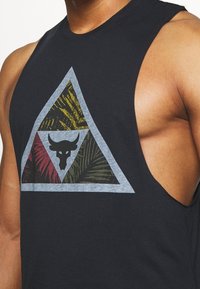 Černý bezrukávový top s velkým trojúhelníkovým potiskem, který zobrazuje zelené, červené a žluté vzory palmových listů a motiv býčí lebky uprostřed.