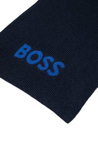 Tmavě modrý žebrovaný šál s výrazným modrým logem "BOSS" uprostřed. Vyrobený z měkkého materiálu s texturovaným povrchem.