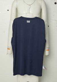 Navy blue sleeveless sports shirt hanging on a torso mannequin with a plastic hanger against a white wall.