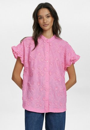 Rosa kortärmad blus med blommönsterbroderi, utställda volangärmar och knäppning fram. Mjuk, texturerad tyg synlig överallt.