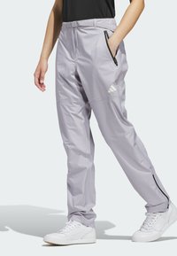 Pantalones deportivos gris claro con un bolsillo con cremallera, cinturilla elástica y diseño de pierna ajustada. Presenta un acento de logo blanco en el costado.