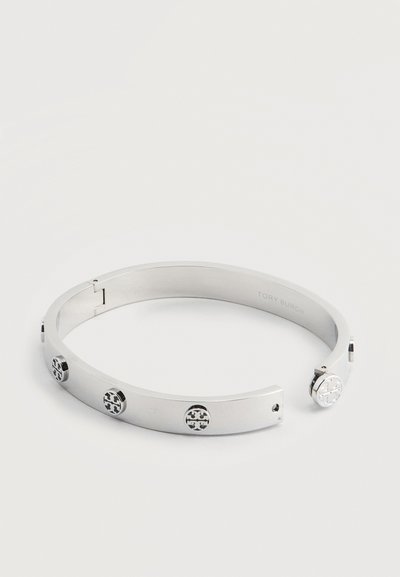 Ασημί μεταλλικό ανοιχτό βραχιόλι με πέντε στρογγυλά εμβλήματα λογότυπου κατανεμημένα ομοιόμορφα γύρω από τη στεφάνη.