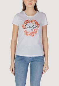 Weißes Baumwoll-T-Shirt mit kurzen Ärmeln, versehen mit einem orangen und goldenen Blumenmuster und dem Schriftzug "Liu Jo" in geschwungener Schrift, zentral platziert.