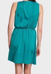Teal, sleeveless dress featuring a cinched waist and flowing skirt. Smooth, shiny fabric with a relaxed fit. No notable patterns or accents.