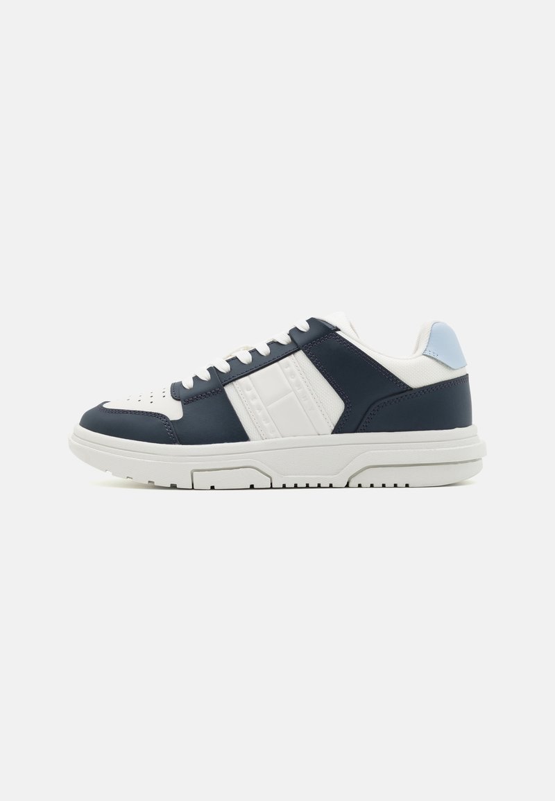 Sneakers med övre del i marinblått läder och vita detaljer, perforerat tåparti och en vit gummisula. Minimalistisk design med vadderad krage.