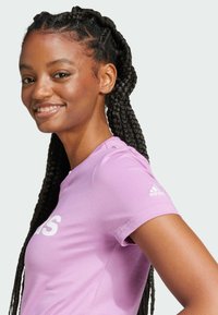 Fioletowy sportowy t-shirt z krótkimi rękawami, zdobiony dużym białym logo i emblematem adidas na lewym ramieniu; gładka faktura materiału.