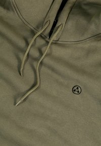 Felpa verde oliva con scollo a V e cordini. Presenta un piccolo logo nero sul petto. Texture morbida, design casual.