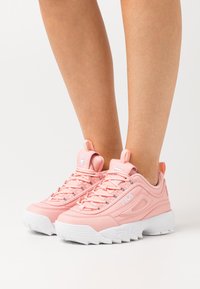 Rosa syntetiske sneakers med teksturert detaljering, hvit gummisåle og snøringsdesign. Har logo aksenter og hantrekk på hælen.