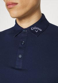 Navy blue polo shirt with a soft texture, three-button placket, and embroidered "Callaway" logo on the collar.
