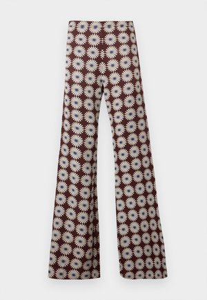 Pantalon marron évasé avec un motif répétitif de marguerites blanches aux centres bleus, présenté sur un fond gris clair uni.