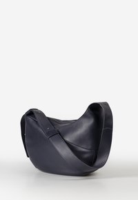 Borsa a spalla in pelle blu navy con forma curvilinea, tracolla regolabile e superficie morbida. Presenta un hardware minimale per un design elegante.