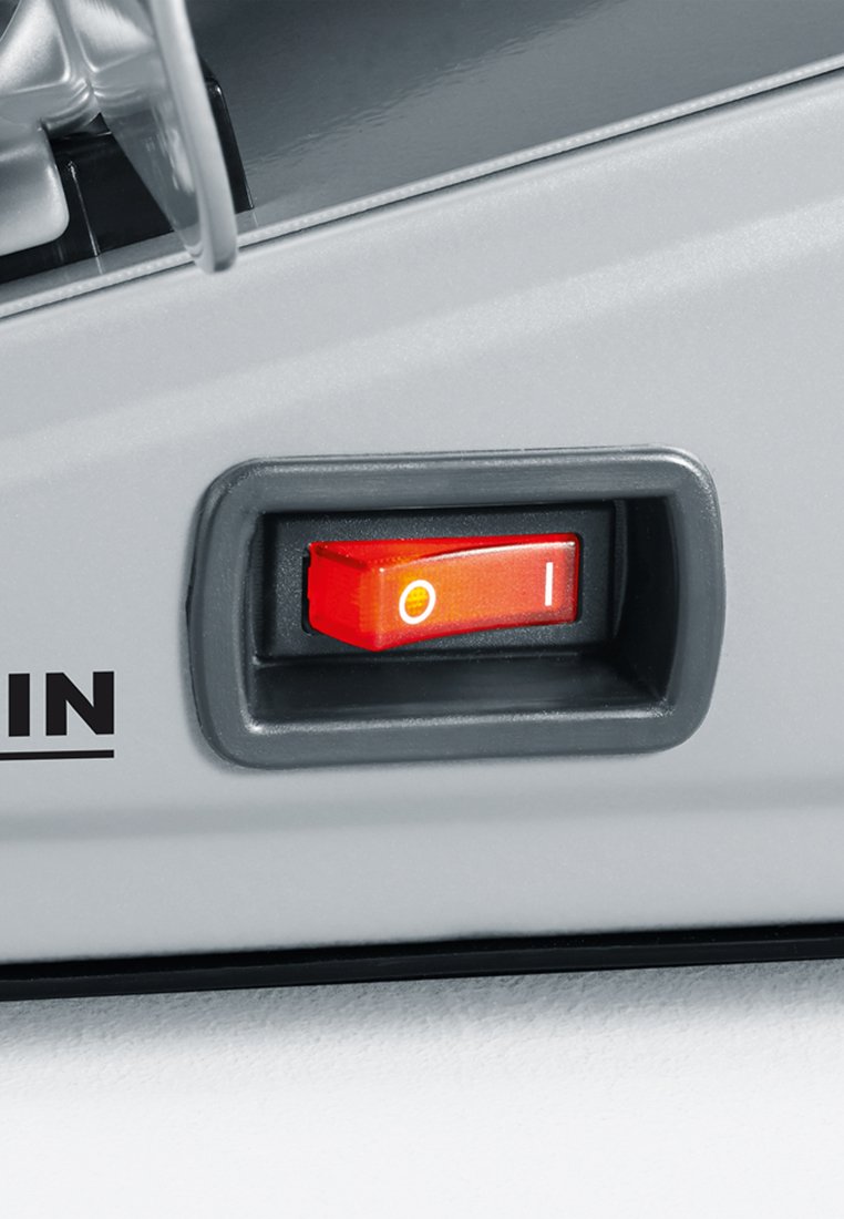 Interruttore rosso con indicatori "O" (spento) e "I" (acceso) sulla superficie di un dispositivo grigia, su uno sfondo chiaro.