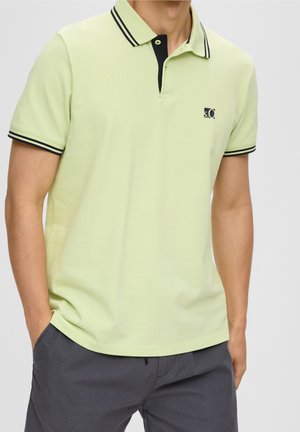 Polo shirt vert clair en coton avec un col classique, des finitions noires et un petit logo sur la poitrine. Manches courtes, tissu texturé.