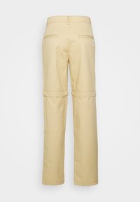 Pantalons cargo beiges à coupe décontractée, avec une ceinture, deux poches arrières et des sections de genoux zippées pour un ajustement de longueur optionnel.