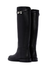 Stivali alti fino al ginocchio in pelle nera con texture liscia, suole piatte e un accento argentato sulla cinghia vicino al polsino. Design minimalista.