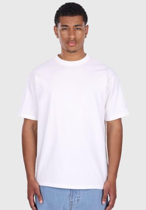 T-shirt blanc à manches courtes en coton, doté d'un col rond classique et d'un ourlet droit, porté avec un jean en denim bleu clair.