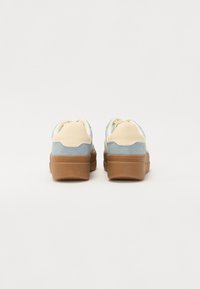 Baskets bleu clair et beige avec une tige en daim doux et une semelle en caoutchouc marron ; elles présentent un bout arrondi et un col rembourré.