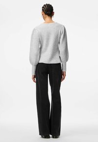 Gaiši pelēks adīts džemperis ar pūkainām piedurknēm, noapaļota kakla izgriezuma, ribotu faktūru, kopā ar augstiem melniem platiem biksēm.