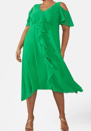 Robe en chiffon vert avec de courtes manches froides, décolleté en V et des volants en cascade, présentant un ourlet asymétrique et une texture légère.