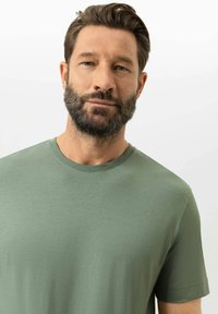 T-shirt vert à manches courtes en tissu lisse, doté d'un col rond et d'une coupe décontractée, sans motifs ni graphismes visibles.