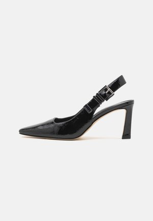 Chaussure à talon haut slingback en cuir verni noir à bout pointu avec bride réglable à boucle sur fond blanc uni.
