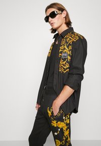 Versace Jeans Couture CHAIN - Trainingsbroek - black/gold