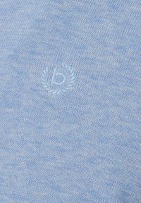 Hellblaues gestricktes Gewebe mit einem tonal gestickten Kleinbuchstaben "b", umgeben von einem Lorbeerkranz.