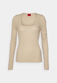 Pull beige à manches longues avec un col carré, une texture côtelée et un léger éclat. Comprend une étiquette rouge à l'arrière du col.