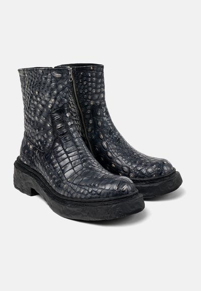 Botas de cuero negro con un patrón texturizado de cocodrilo, que cuentan con una cremallera lateral y una suela gruesa y texturizada.