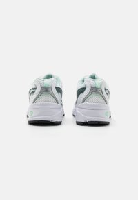 Białe buty sportowe z miętowymi akcentami, siateczkowa cholewka, wyściełana podeszwa i zaokrąglony obcas. Wyprofilowany kołnierz dla wsparcia i komfortu.