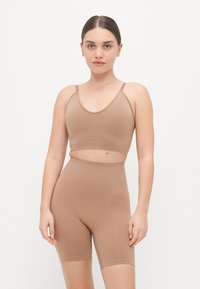 Sada bralet a vysokými šortkami s odhaleným bruchom v tan farbe, vyrobená z hladkého, elastického materiálu s tenkými ramienkami a bezšvovým dizajnom.