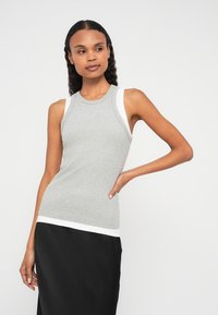 Top cinzento canelado sem mangas com acabamento branco, design justo e decote redondo, combinado com saia preta. Textura suave, estilo casual.