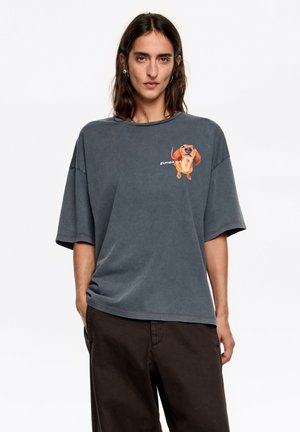 Szara, oversize'owa koszulka wykonana z miękkiej tkaniny, z krótkimi rękawami i zabawnym nadrukiem psa na piersi.