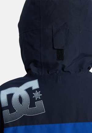 Marineblaue Kapuzenjacke mit blauen Akzenten, ausgestattet mit einem großen weißen Logo und Sternen Design auf dem Rücken. Hergestellt aus glattem, wetterbeständigem Material.